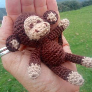 Little mini crochet monkey on the palm of the hand